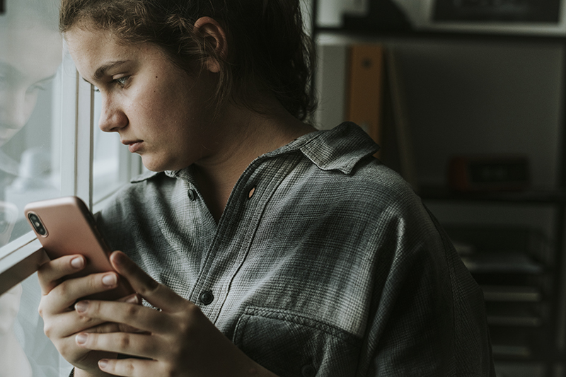 young woman looking out the window in distress